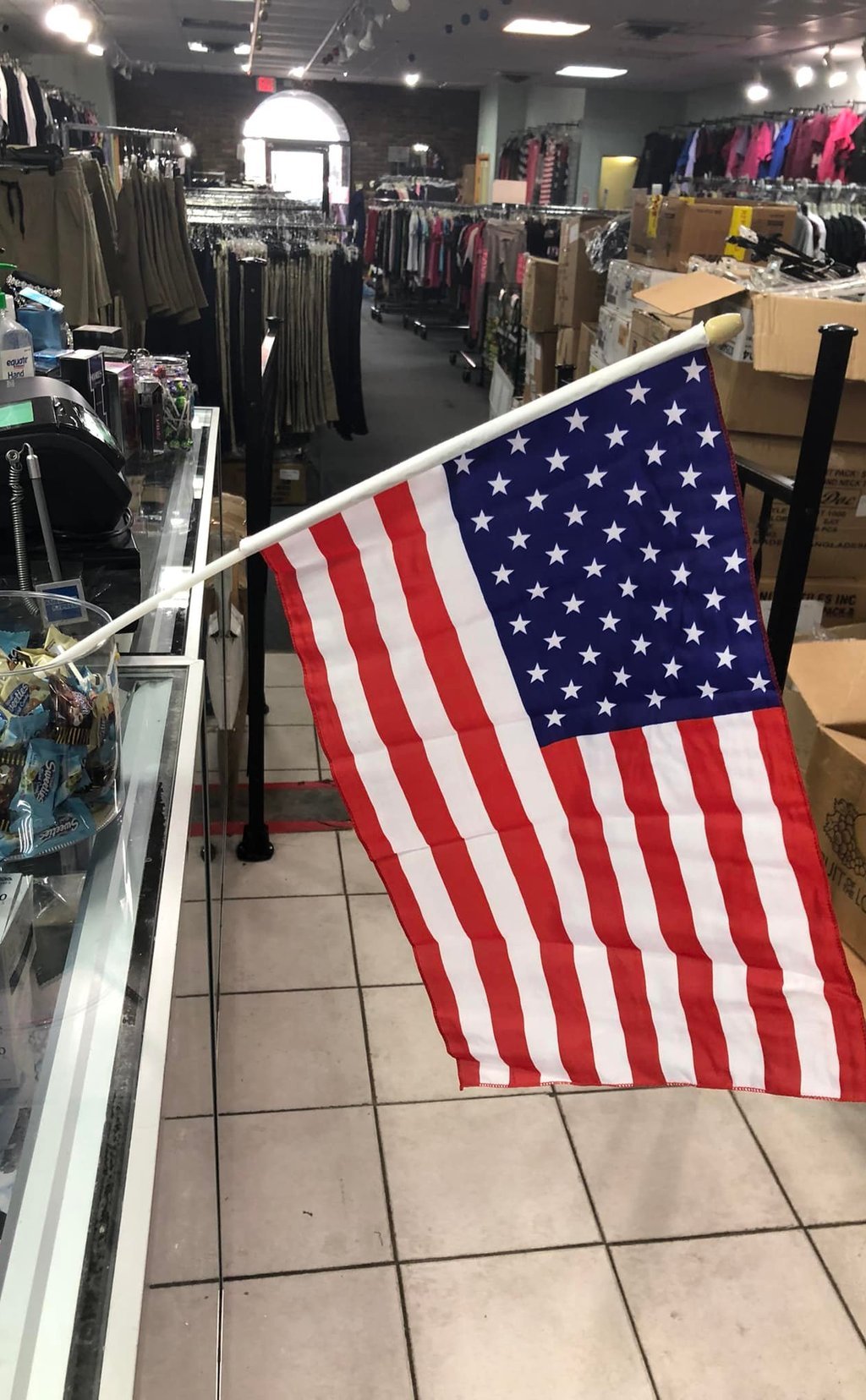 Interior of the B-Uniform store, racks of uniforms with an American flag displayed near the checkout counter