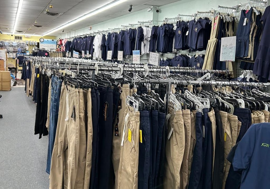 Rows of navy and khaki uniform pants and polos on store racks