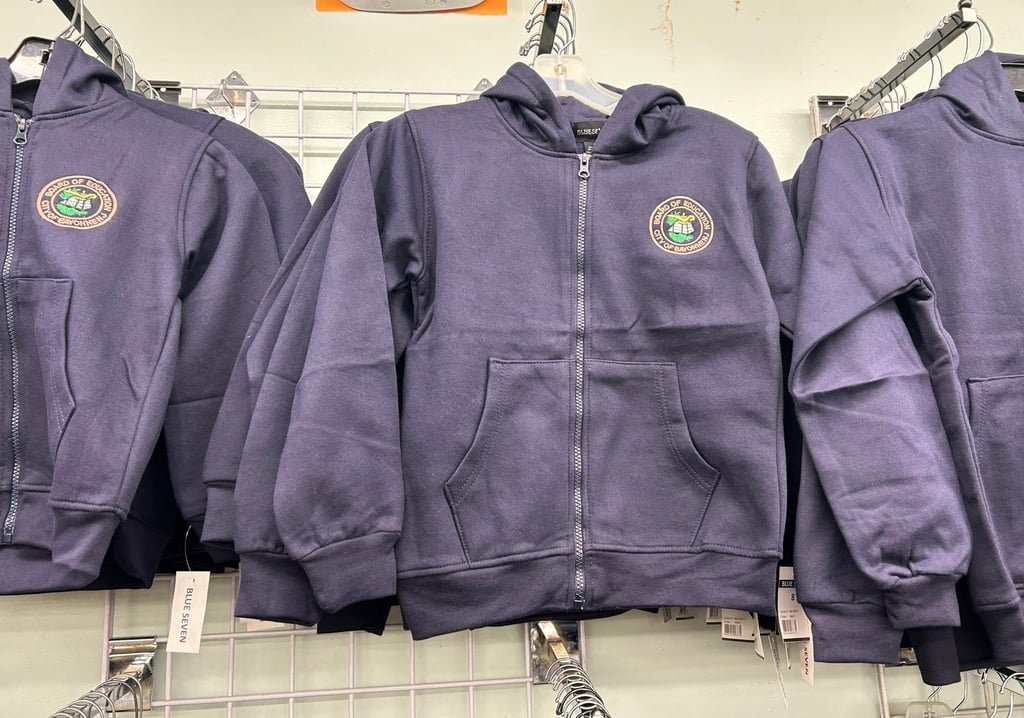 Navy zip-up hoodies with the Bayonne Board of Education logo on hangers
